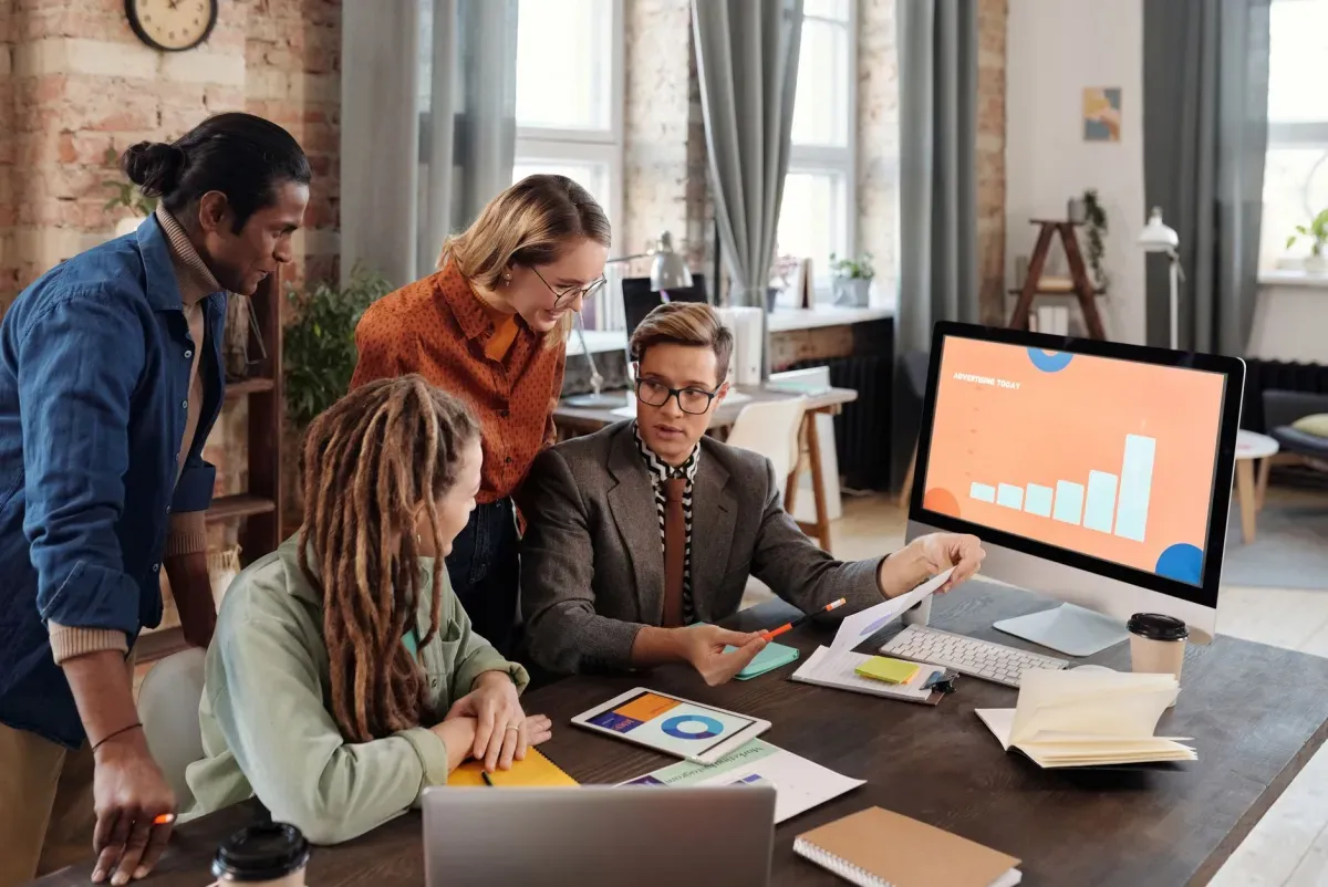Equipe de marketing analisando gráficos em um monitor no escritório