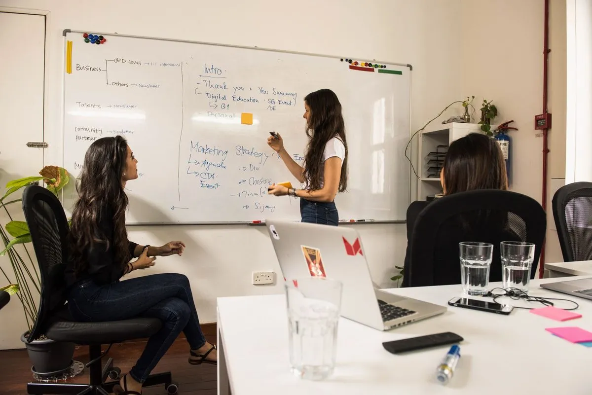 Equipe de marketing reunida em frente a um quadro branco, discutindo a estratégia de uma campanha.