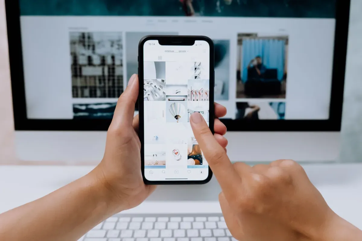 Pessoa navegando em um site pelo celular em frente ao computador