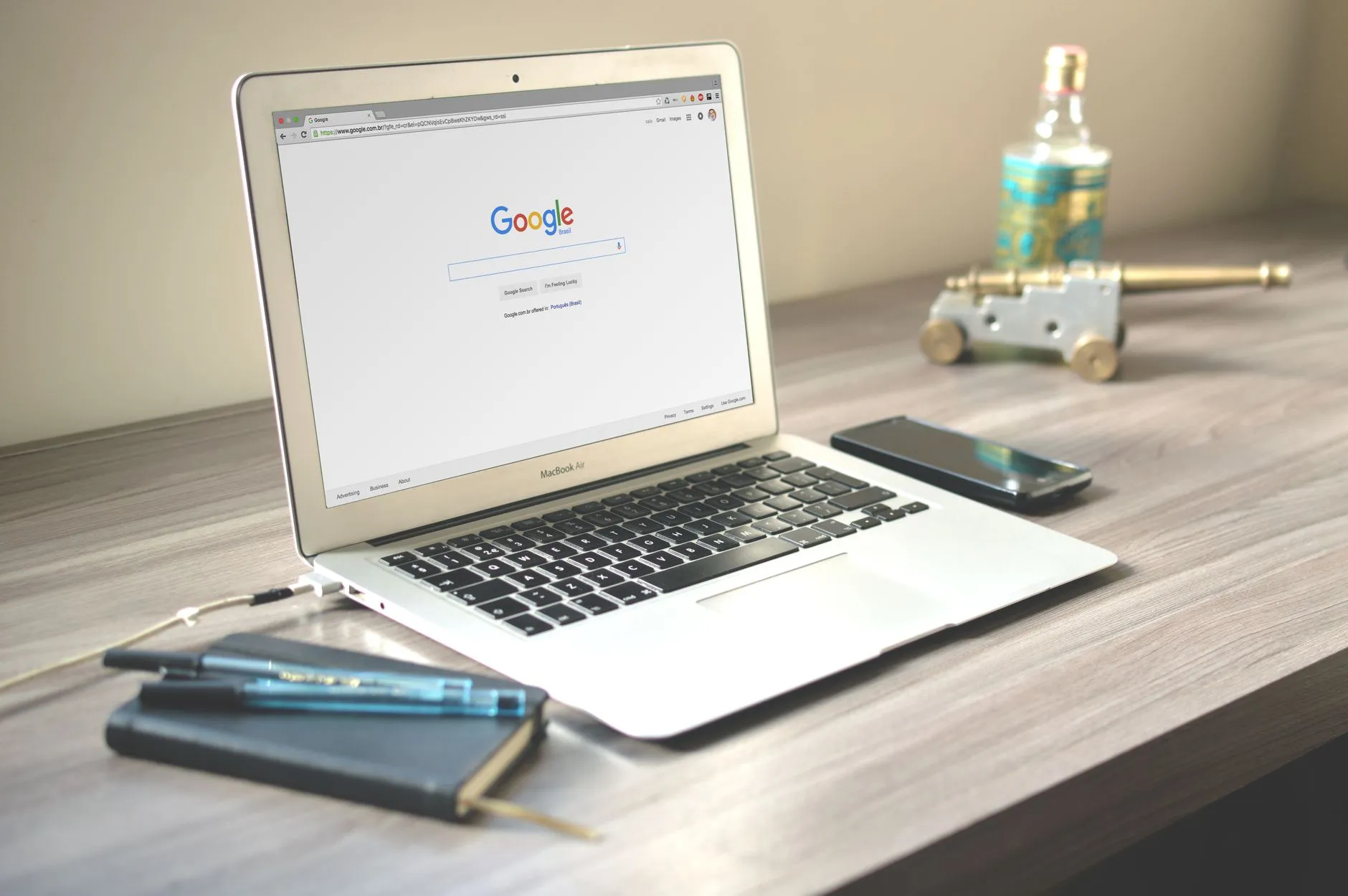 Notebook aberto na página de busca do Google sobre uma mesa de madeira