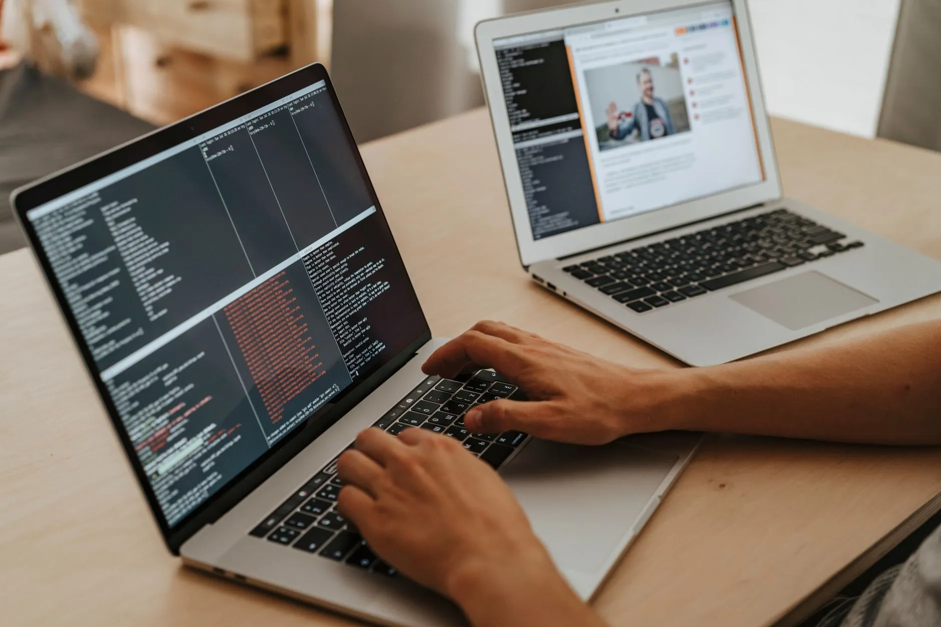 Pessoa programando em dois notebooks com código na tela