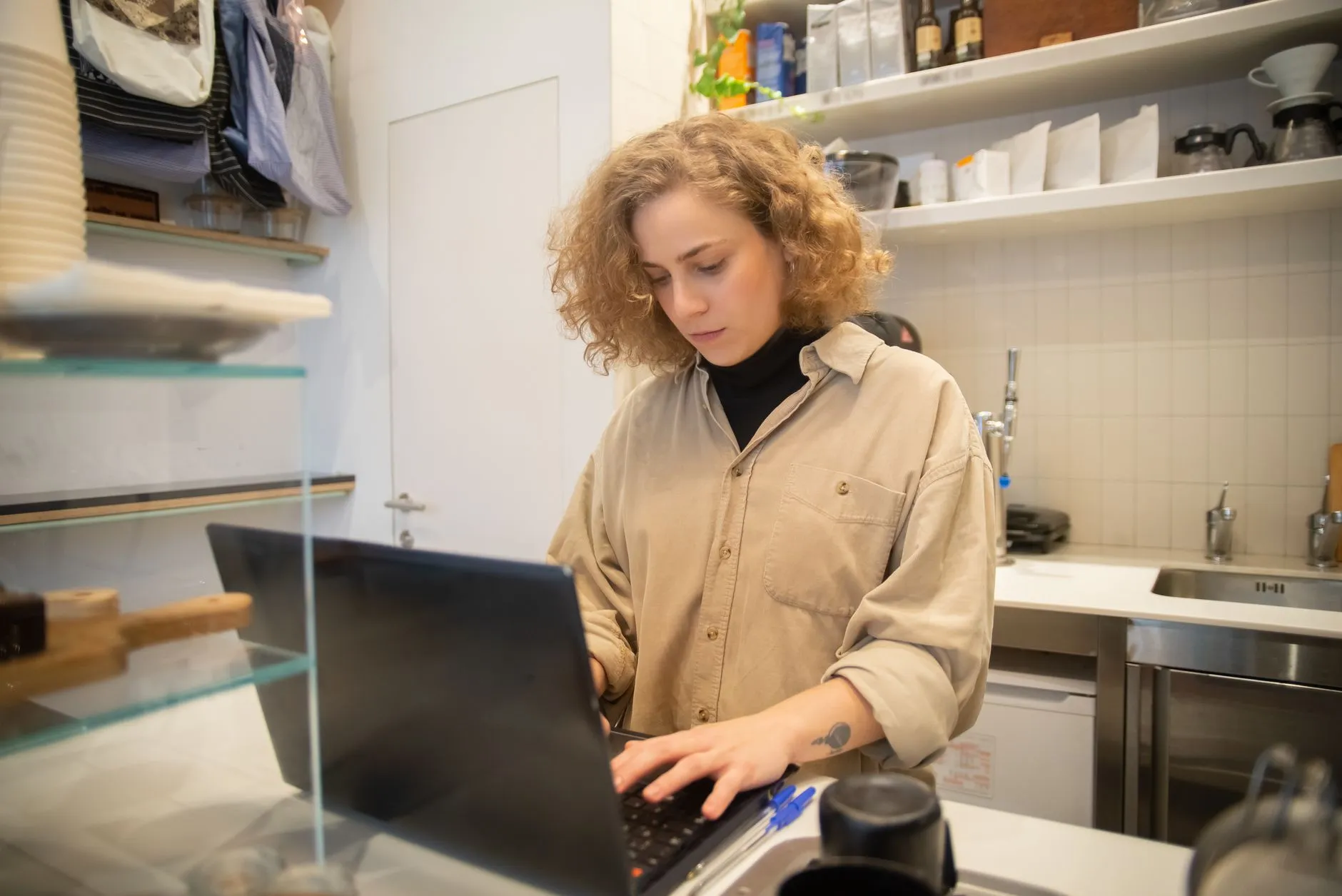 Dona de um pequeno comércio trabalhando no notebook atrás do balcão